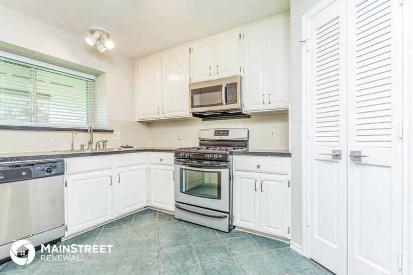 a kitchen with white cabinets and stainless steel appliances
