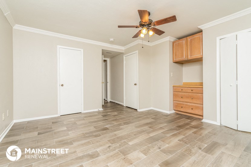a living room with white walls and a ceiling fan