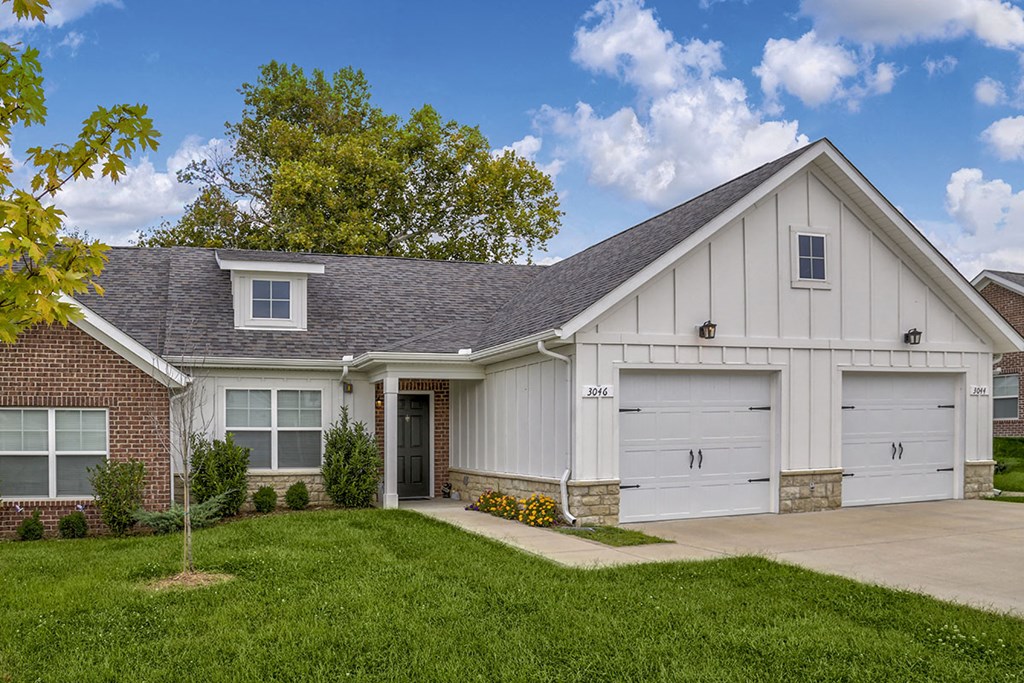 a white and brick house with a driveway and garage doors