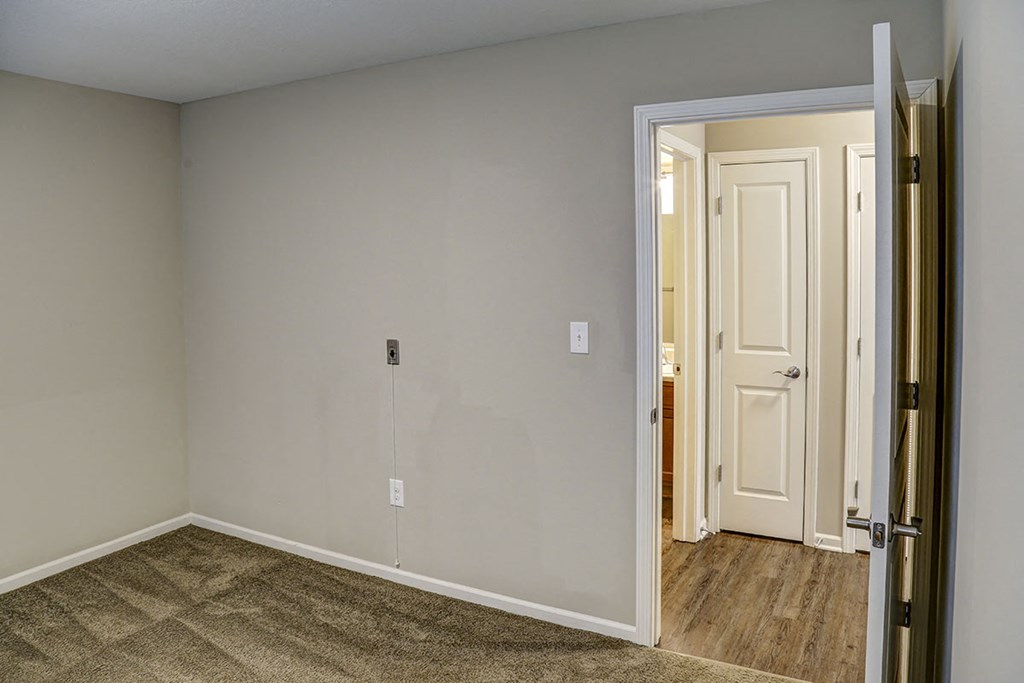 an empty bedroom with a door open to a hallway