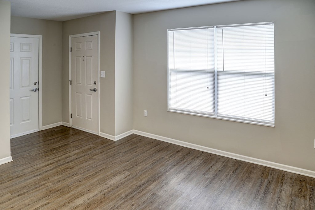 an empty living room with wood flooring and a window
