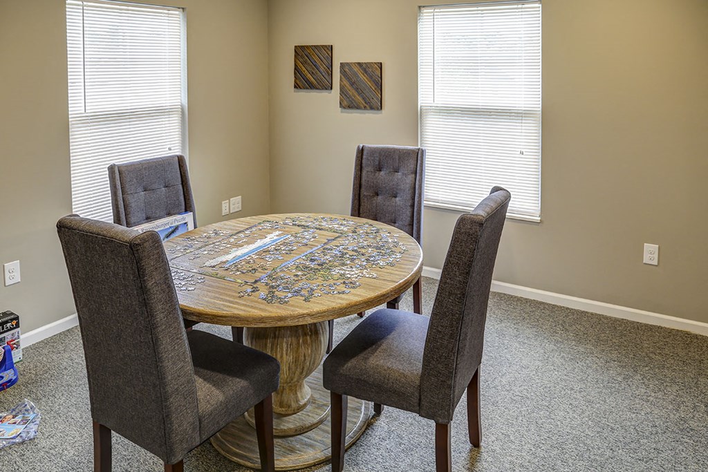 a dining room table with four chairs and two windows