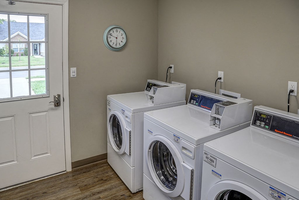 a laundry room with four washing machines and a clock on the wall