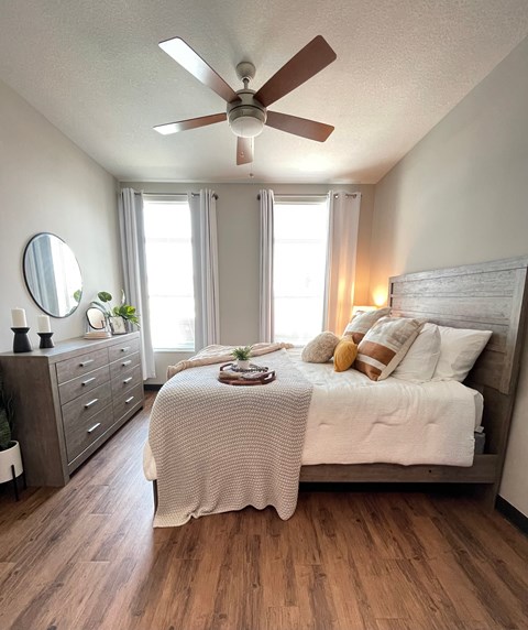 A bedroom with a bed, dresser, and ceiling fan.