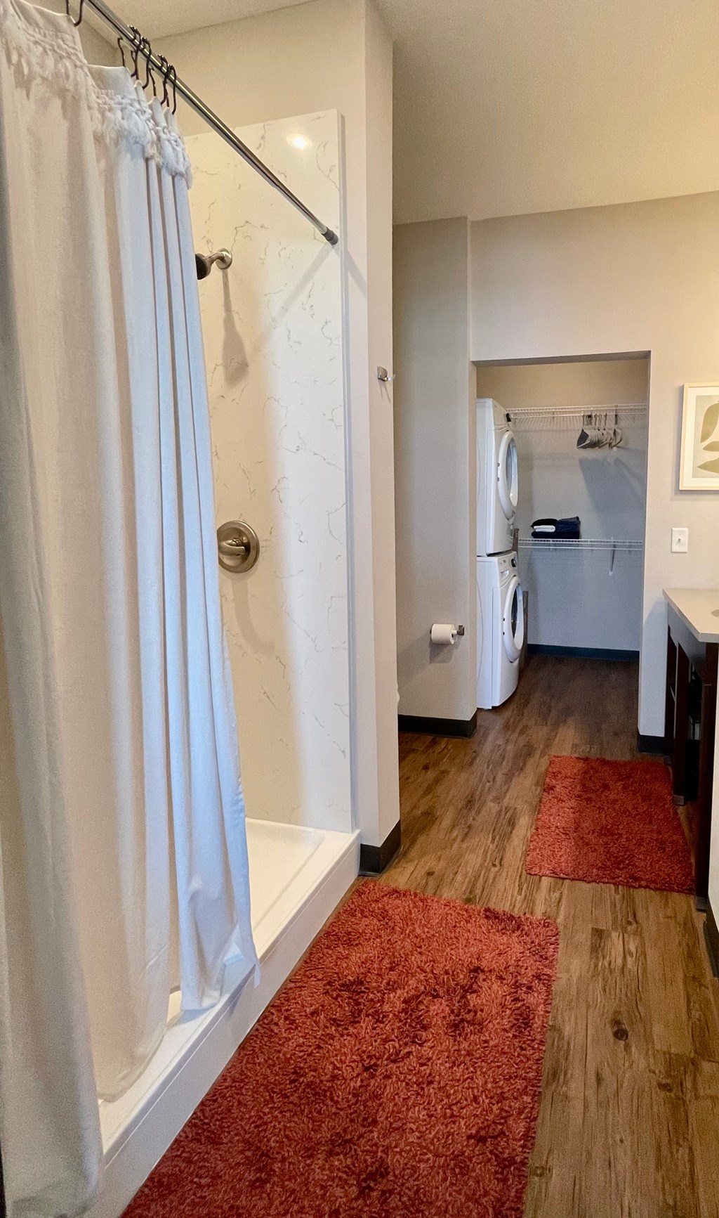 A bathroom with a white shower curtain and a red rug.