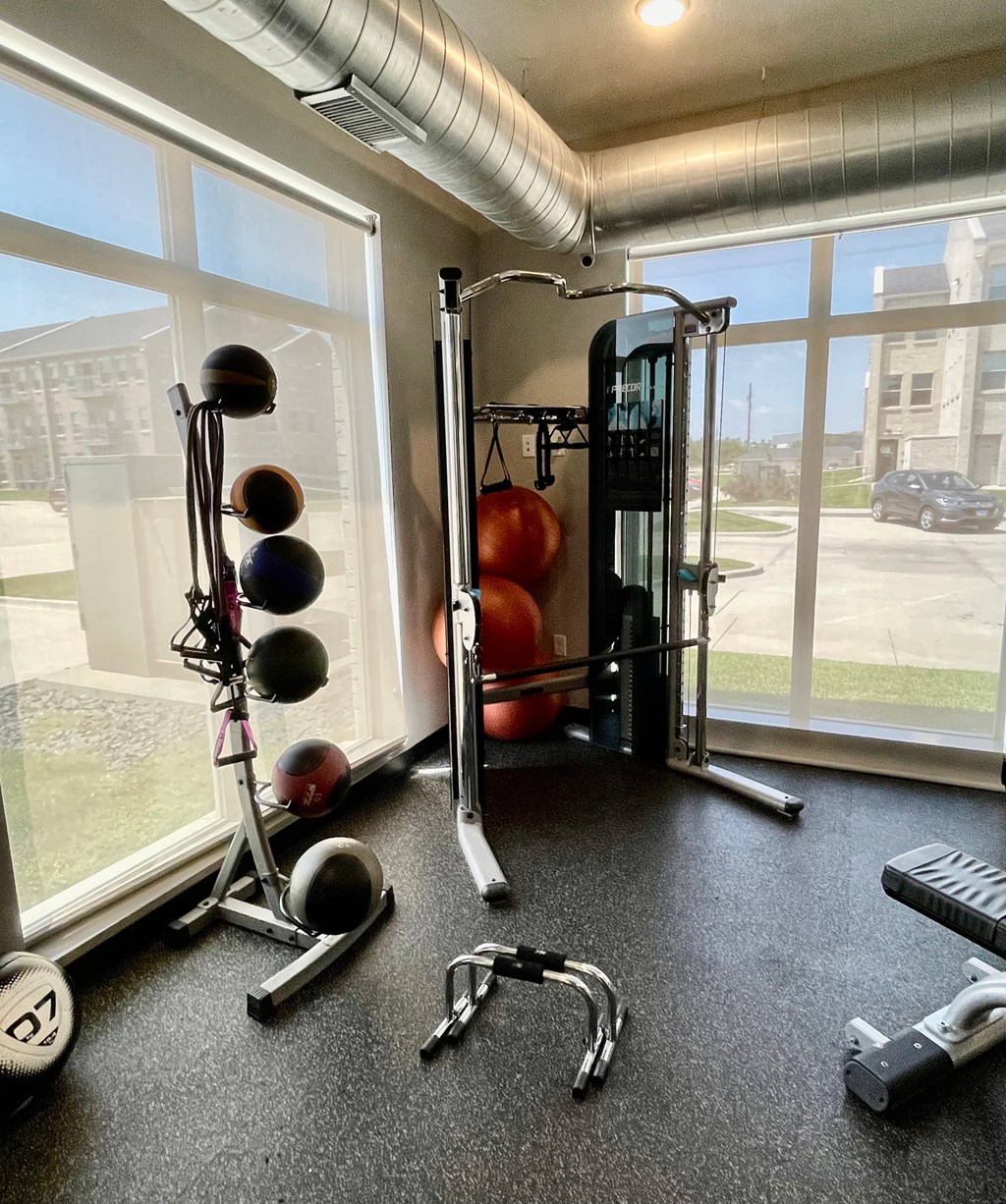 A home gym with a variety of equipment including a weight rack, dumbbells, and a bench.