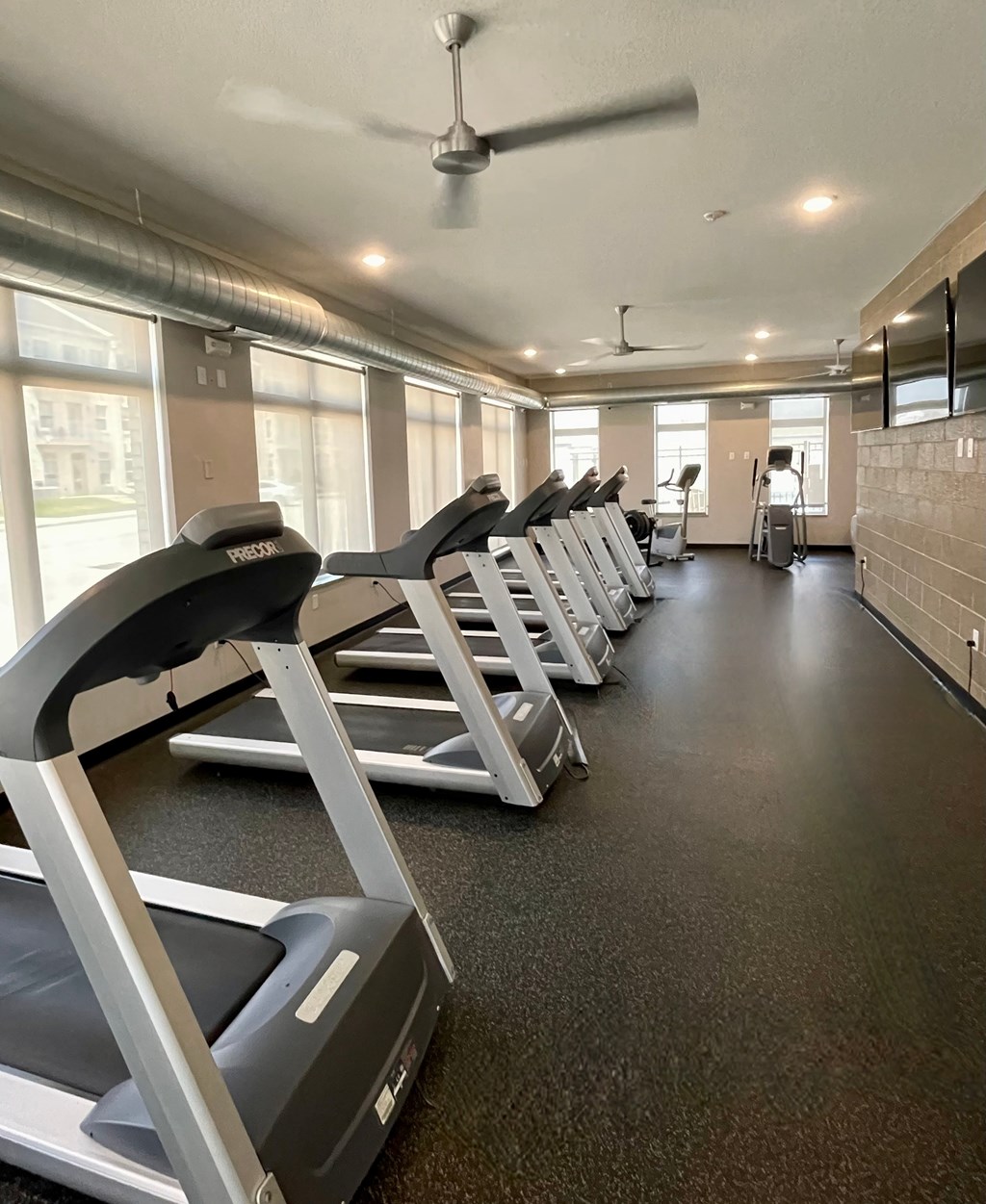 A gym with treadmills and a fan.