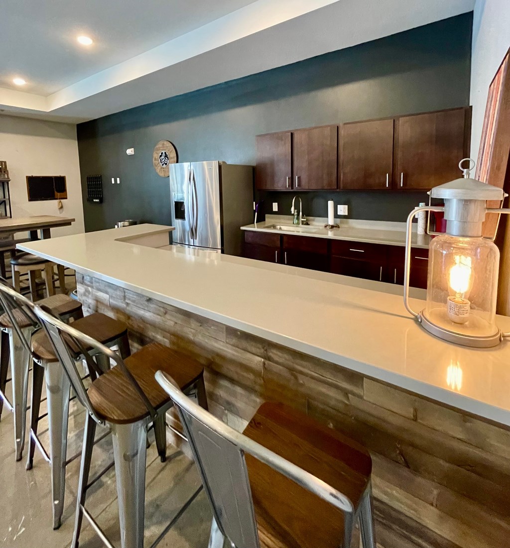 A kitchen with a white counter top and a refrigerator in the middle.