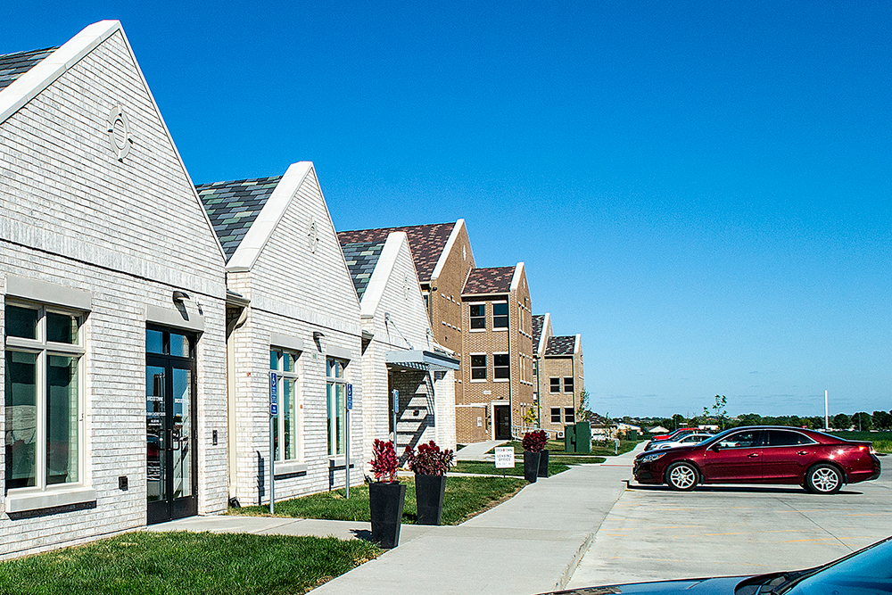 A row of houses with a red car parked in front of the last one.