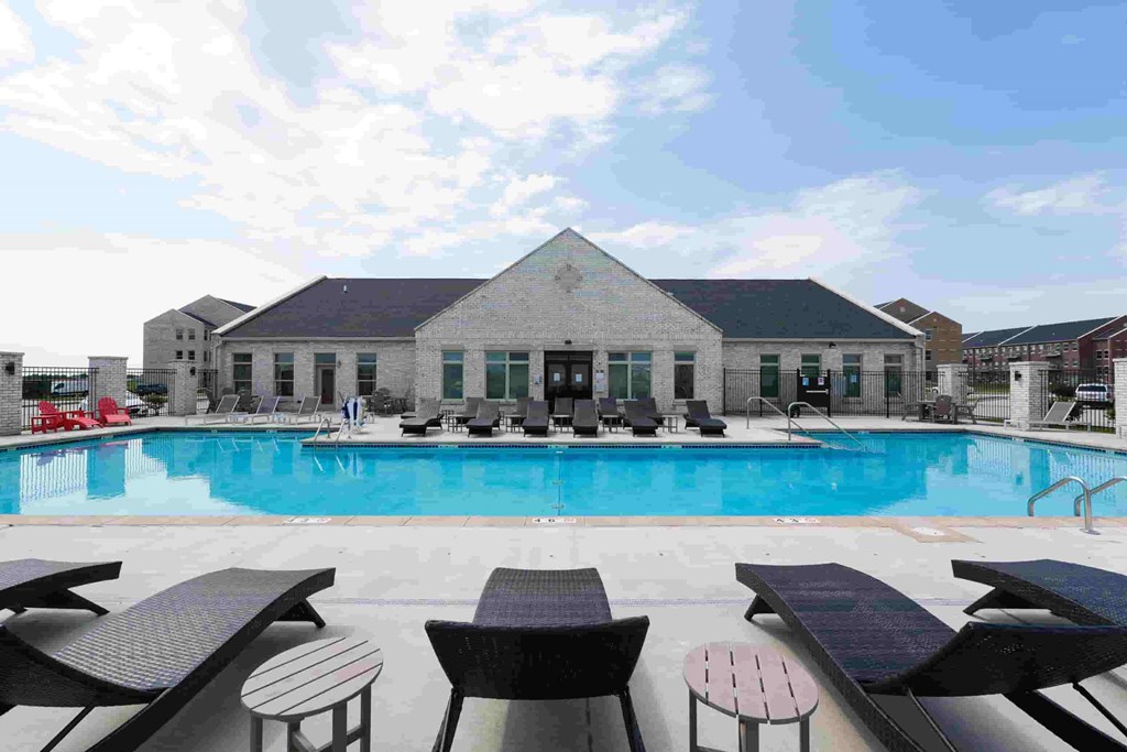 A pool with sun loungers and a building in the background.
