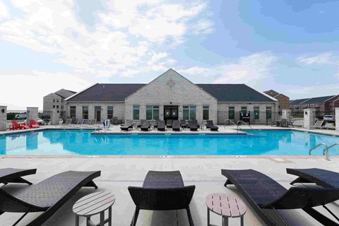 A pool with sun loungers and a building in the background.