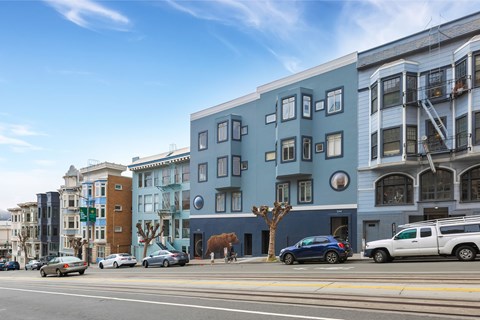 A street view of a city with cars, buildings, and a blue sky.