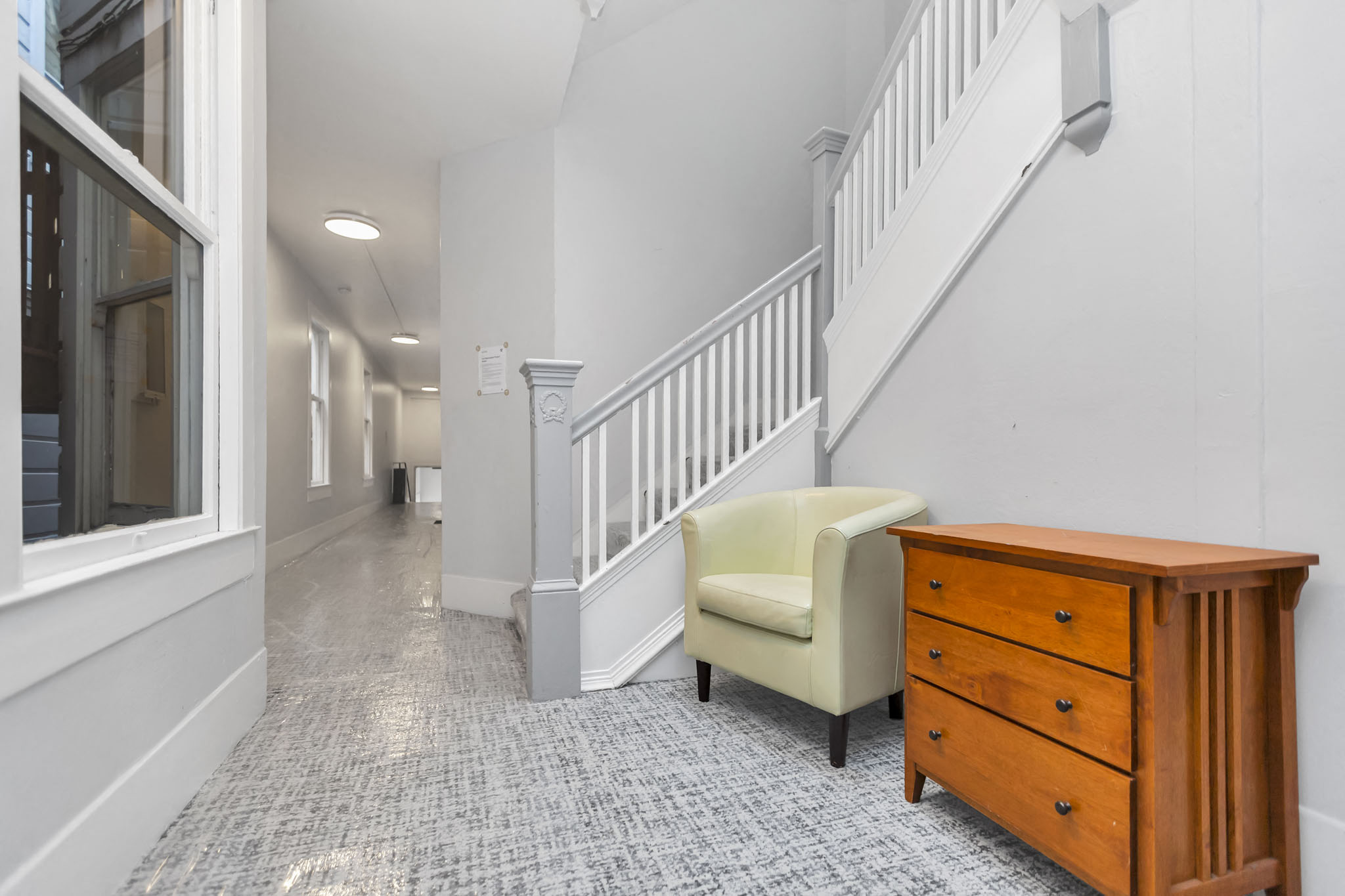 A hallway with a chair and a dresser.