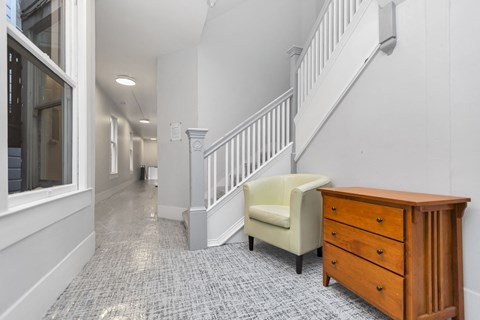 A hallway with a chair and a dresser.