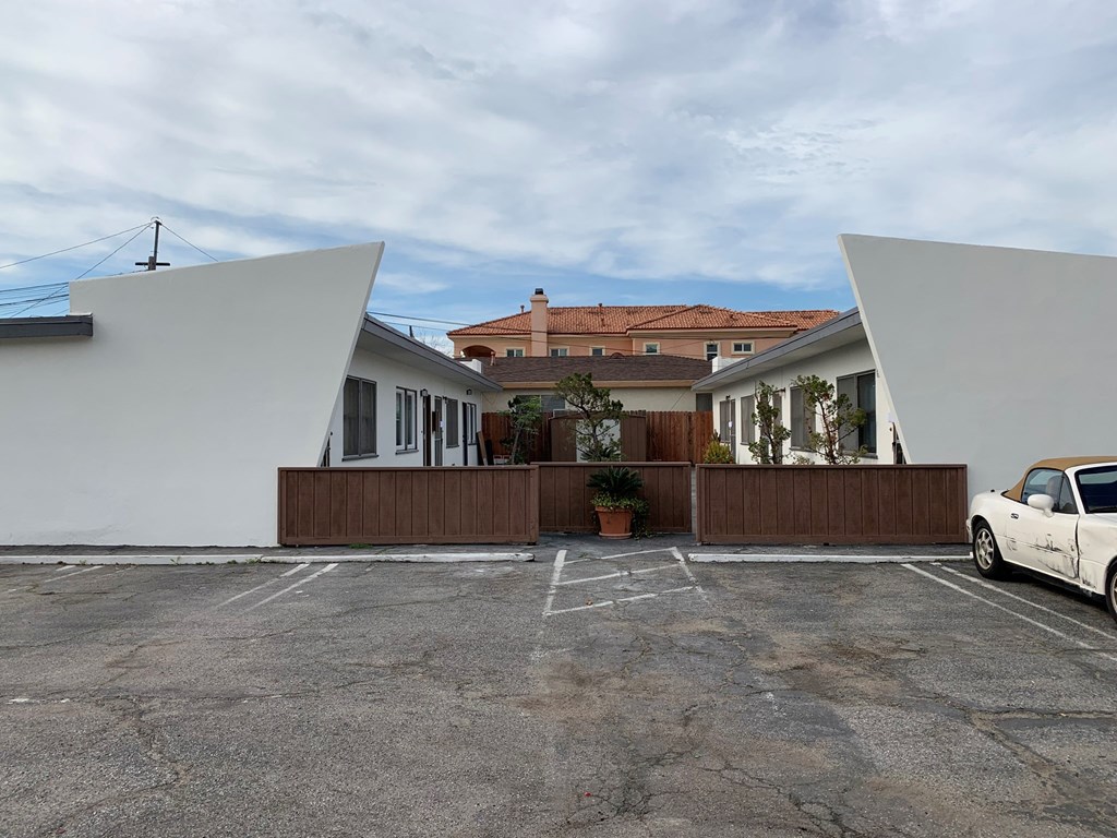 a row of white houses with a parking lot and a car