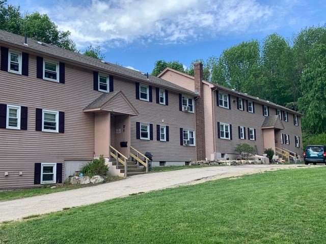 a large apartment building with a driveway and a green lawn