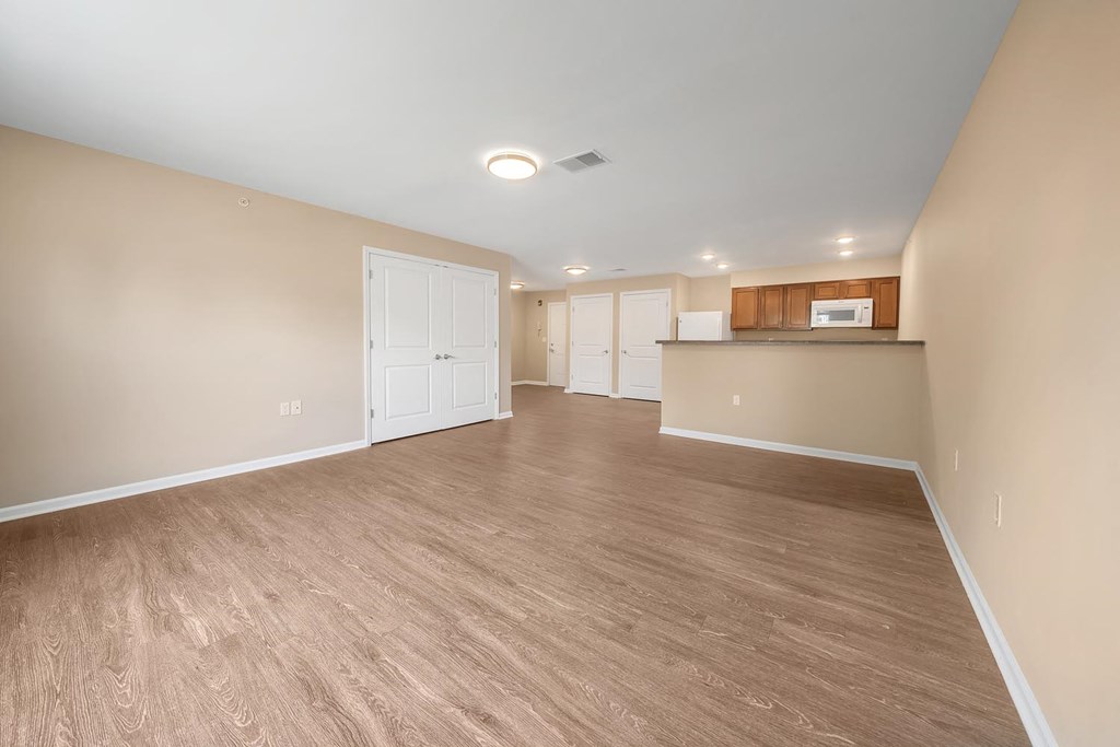 an empty living room and kitchen with wood flooring