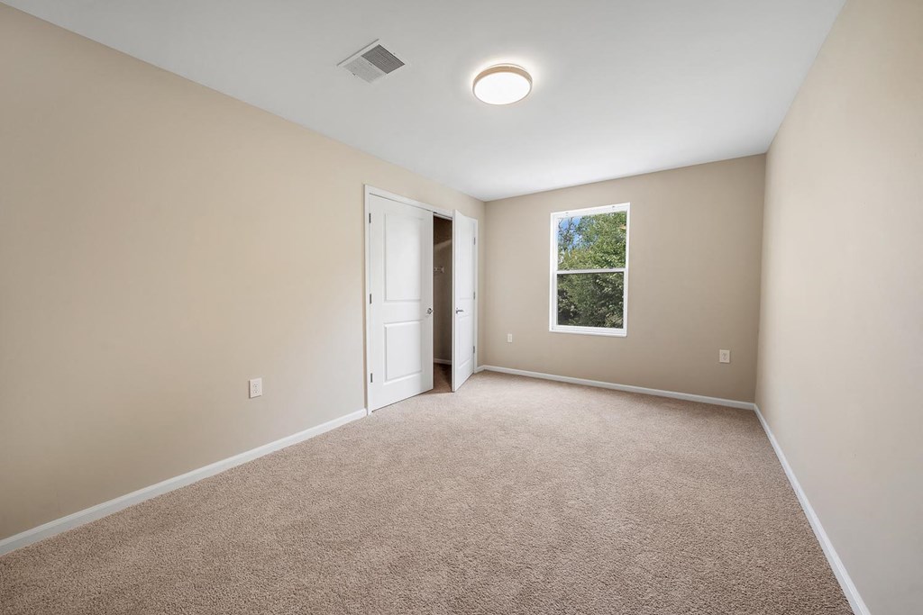 an empty room with carpet and a door to a closet