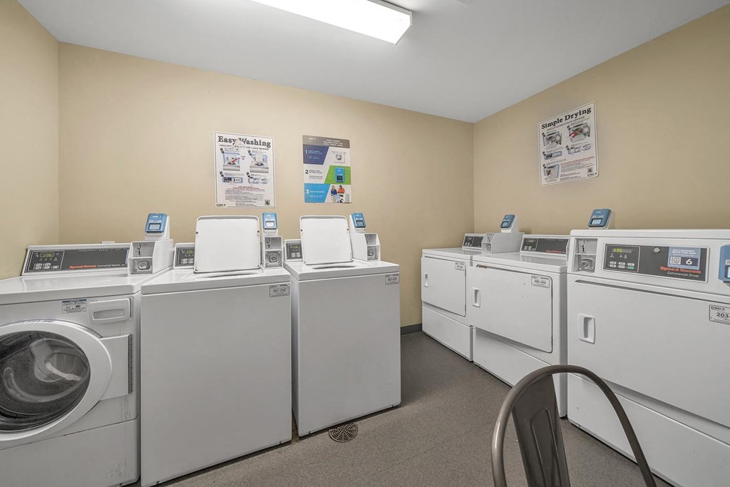 washing machines and dryers in a laundry room with notices on the wall