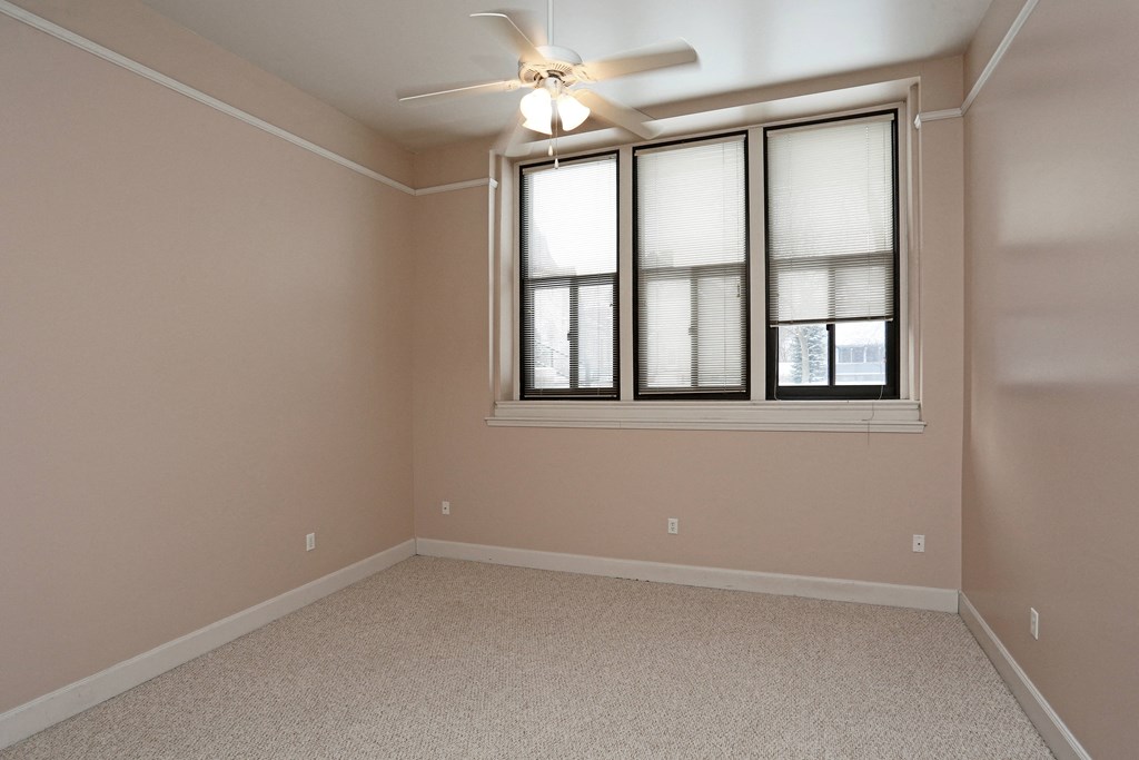 A room with a ceiling fan and a window with blinds.