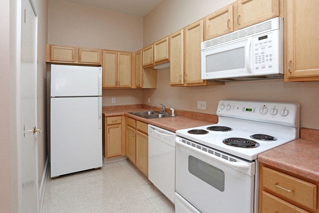 A kitchen with white appliances and wooden cabinets.