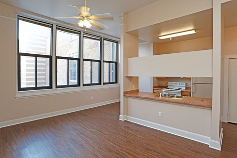 A room with a ceiling fan and large windows.