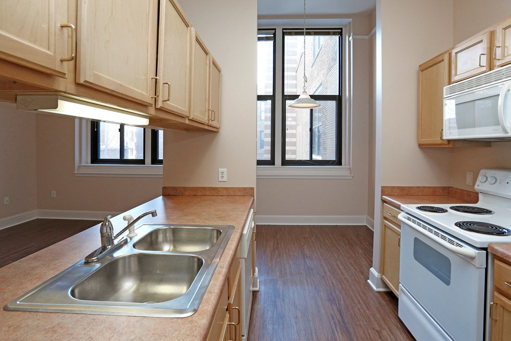 A kitchen with a stove, sink, and cabinets.