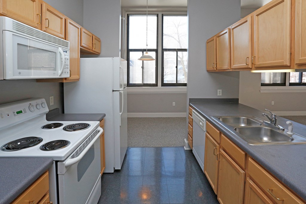 A kitchen with a white stove top oven and a white microwave above it.