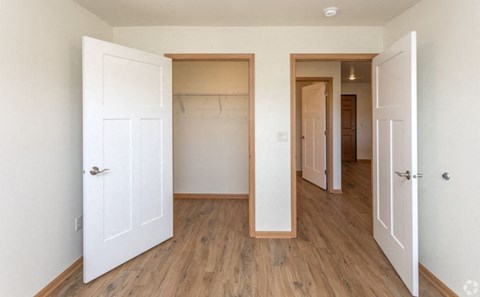 A room with a white door and a wooden floor.