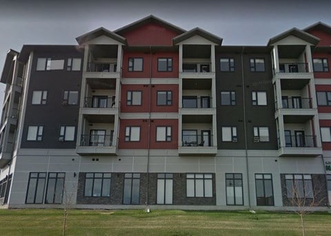 a building with many balconies and a grass field