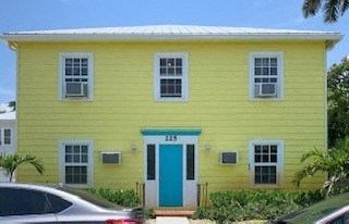 a yellow house with a blue door and a parking lot