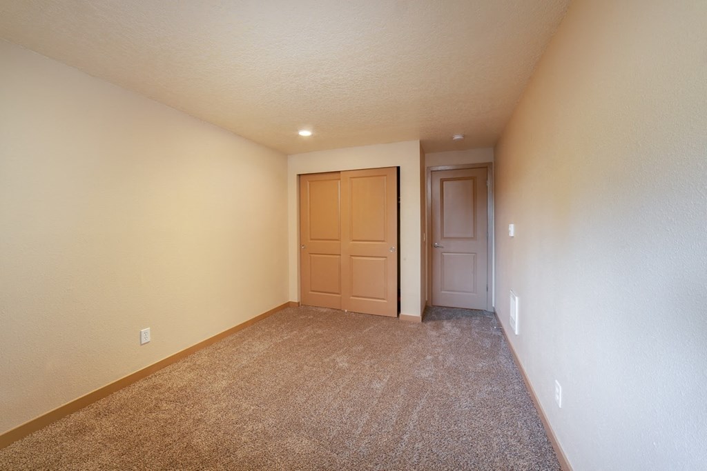 a empty living room with a door to a closet