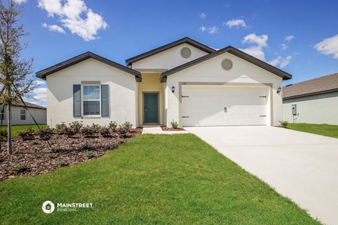 a white house with a garage door and a lawn