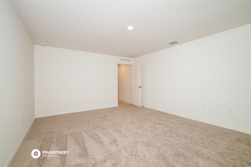 a spacious living room with carpet and white walls