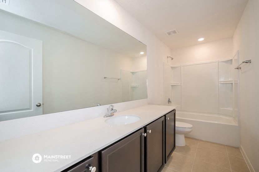 a bathroom with a large mirror and a sink and a toilet