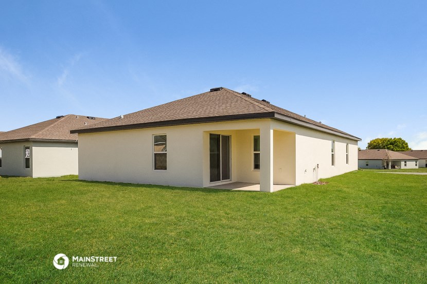 the backyard of a white house with a lawn and a blue sky