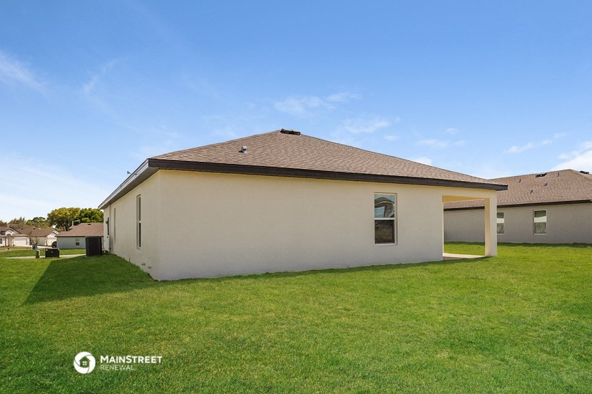 the backyard of a house with a lawn and a blue sky