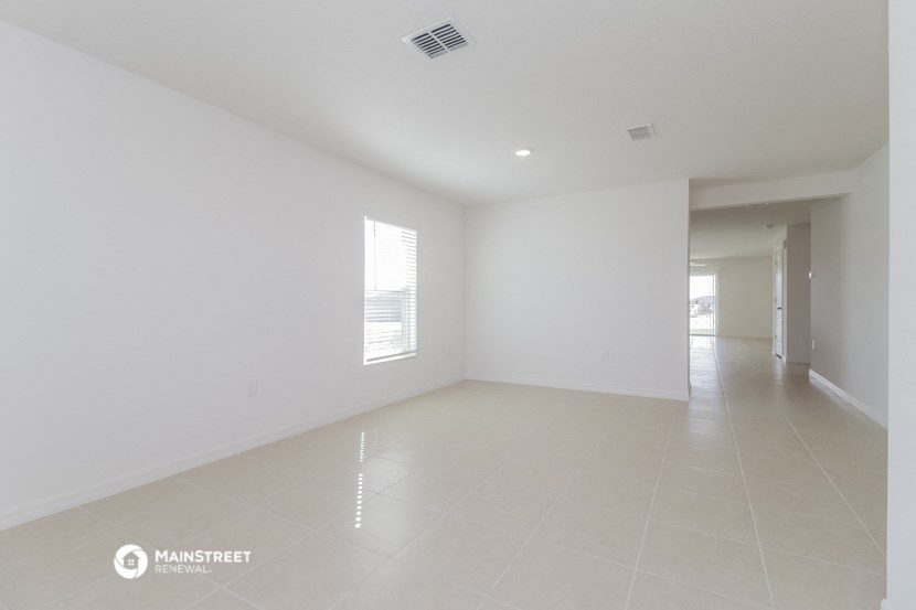 an empty living room with white walls and tile floor