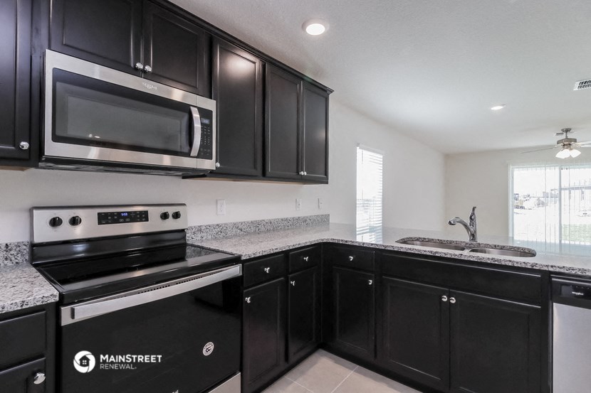 the kitchen of a home with black cabinets and a stainless steel microwave