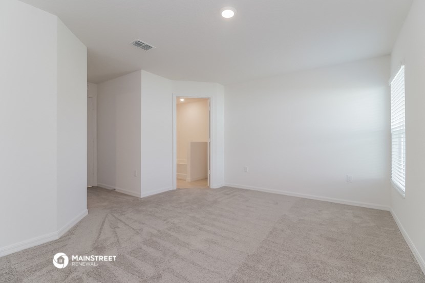a spacious living room with white walls and a carpeted floor