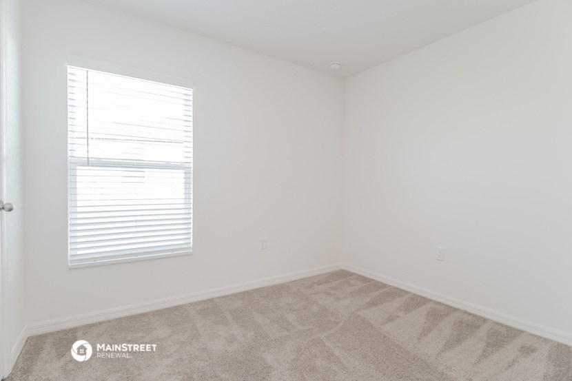 a bedroom with white walls and a window