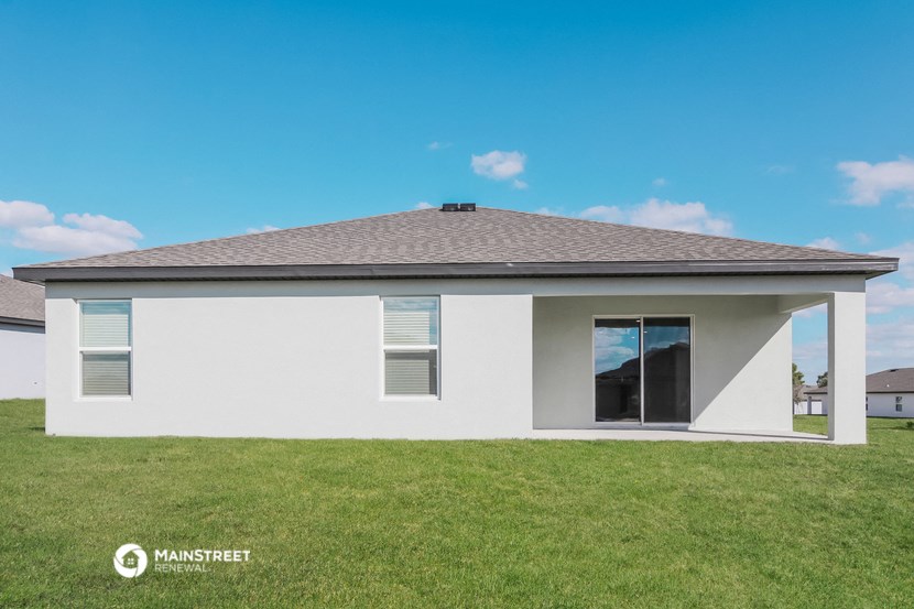 the front of a white house with a grass field