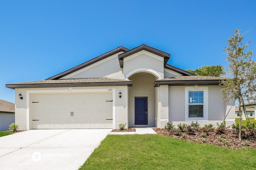 a white house with a garage door and a lawn