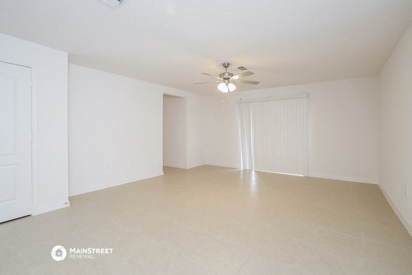 an empty living room with white walls and a ceiling fan