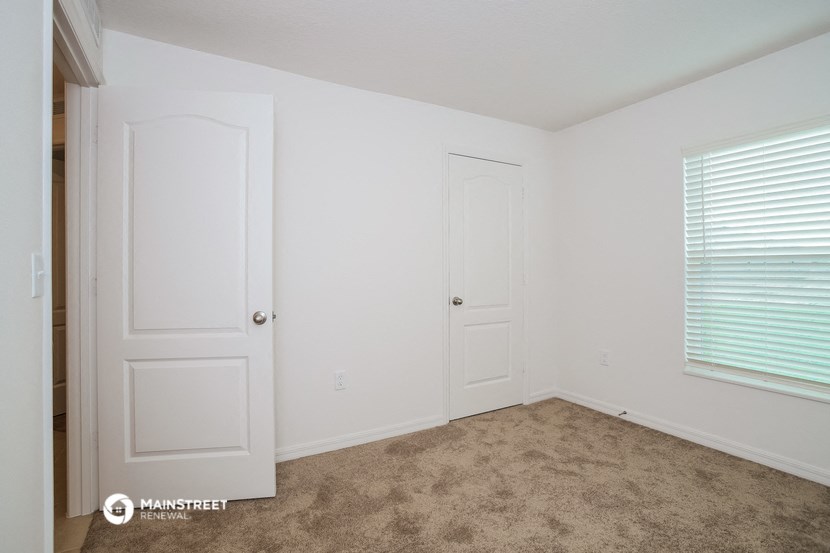 a bedroom with two doors and a carpeted floor and a window