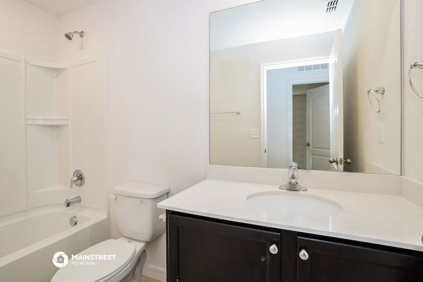 a white bathroom with a large mirror and a toilet and a sink