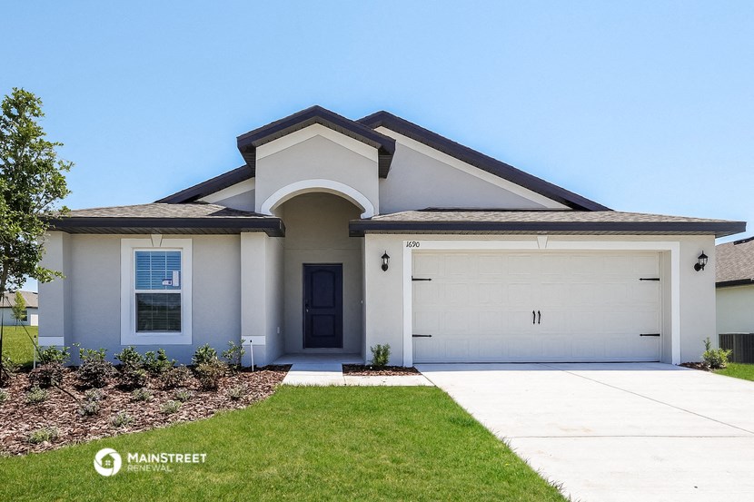 a white house with a garage door and a lawn
