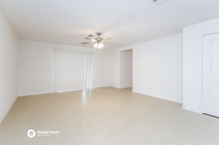 an empty living room with white walls and a ceiling fan