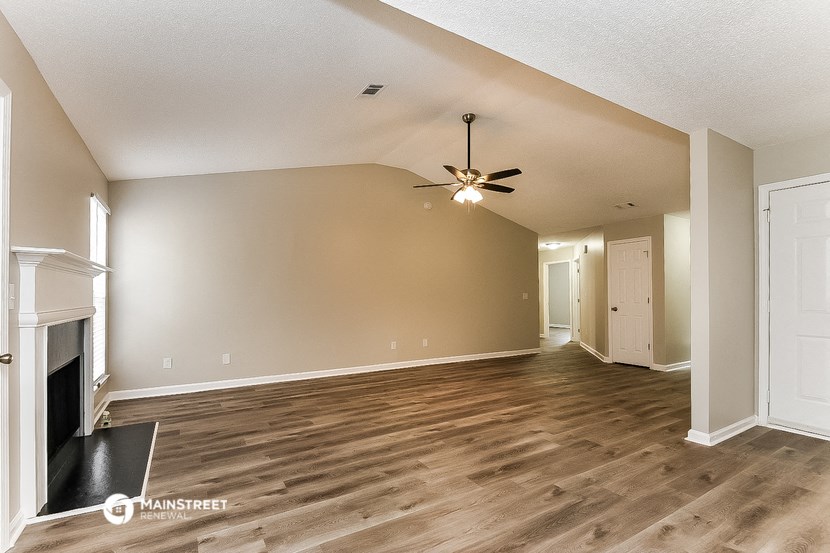 an empty living room with a fireplace and a ceiling fan