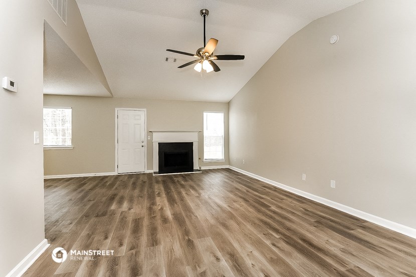 an empty living room with a ceiling fan and a fireplace
